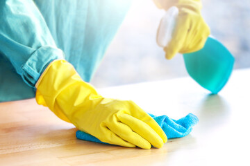 Woman with yellow gloves cleaning the table with spray disinfectant in a restaurant or kitchen. High quality photo