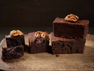 stack of baked pieces of brownie chocolate cake with nuts on a wooden board