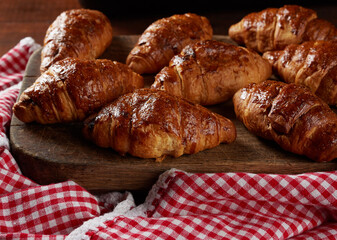 baked croissants on a wooden brown board,