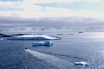 Fototapeta premium Rubber boat in antarctic landscape with blue water, iceberg, glacier, Antarctica