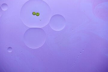 Current collection of brilliant backgrounds for your design. Close-up shot of green oil bubbles and water circles on violet surface with swirls.