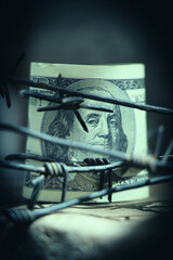 Economic warfare, sanctions and embargo busting concept Barbed wire against US Dollar bill. Close up.