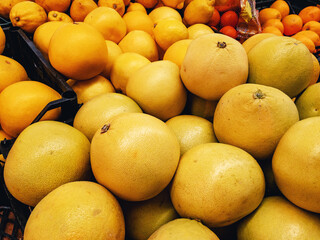 Large ripe yellow fruits of the Pomelo (Latin Citrus māxima) lie in a heap on top of each other.