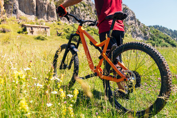wheels of mountain bike and biker on flower meadow