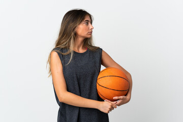 Young woman playing basketball isolated on white background looking to the side