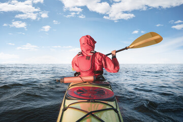 A kayaker rowing in the open sea. Back view.