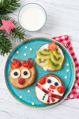 Christmas pancakes in a shapes of deer, tree and snowman made of fresh fruits and berries. Glass of milk. Healthy food for kids ideas. Top view