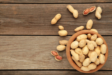 Dried peanuts in wooden bowl on grey wooden background. Vertical foto