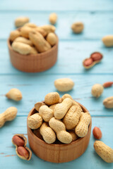 Dried peanuts in wooden bowl on blue wooden background.