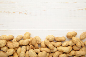 Peanuts in shells on white wooden background