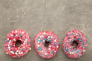 Baked sweet delicious donuts with pastry crumb on gray concrete background. Food texture