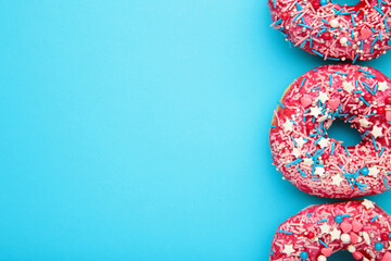 Donuts with icing on pastel blue background. Sweet donuts.