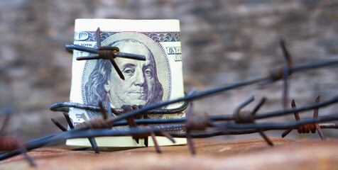 Economic confrontation and warfare, sanctions and embargo busting concept. Barbed wire against US Dollar. Horizontal image.