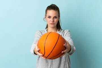 Young caucasian woman isolated on blue background playing basketball