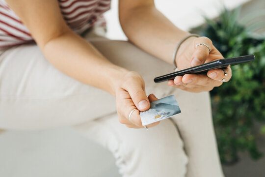 Online shopping. Girl with a cell phone and a credit card or a bank card in hands.
