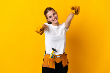 Young electrician woman isolated on yellow background points finger at you while smiling - obrazy, fototapety, plakaty