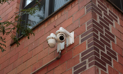 surveillance camera installed on the external brick wall of a residential building for security