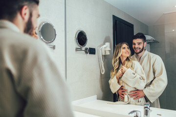 Lovely couple in front of the mirror while getting ready in the bathroom
