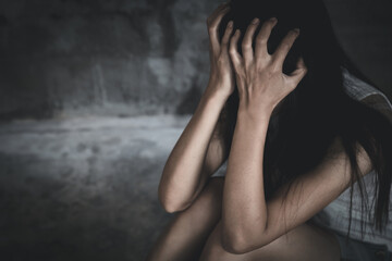 Young  women sitting in dark room feeling pain with life problem.  suffering from husband violence, Stop violence against and sexual abuse women, domestic violence, human trafficking. - obrazy, fototapety, plakaty