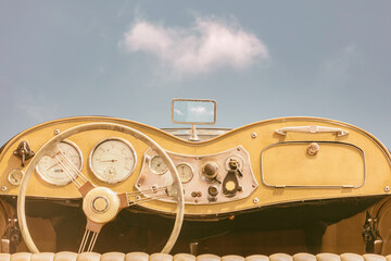 Driver view of a vintage classic open cabriolet car in front of a sunny blue sky