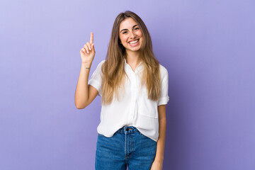 Young woman over isolated purple background pointing up a great idea