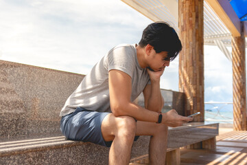 Lonely Asian man sitting in the hut by the sea chilling the atmosphere.