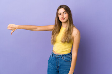 Young woman over isolated purple background showing thumb down with negative expression