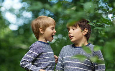 Two lovely brothers sitting in park with flowers hugging