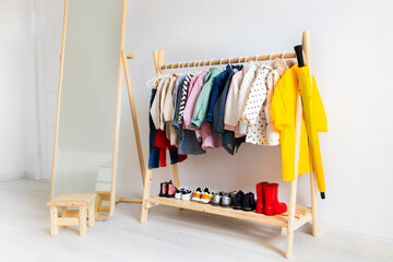 Dressing closet with clothes arranged on hangers. Colorful wardrobe of newborn, kids, toddlers, babies full of all clothes for autumn. montessori wardrobe