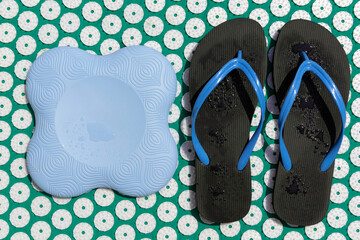Massage acupressure  mat with colorful yoga items and flip flops.