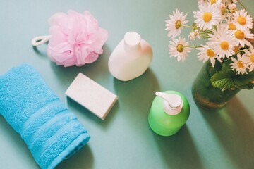 Fototapeta na wymiar Flat lay beauty photography. Rolled blue towel, pink sponge, soap bar, natural shampoo, organic shower gel and chamomile