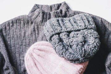 Woolen sweater and pink and gray knitted hats. Flat lay winter fashion
