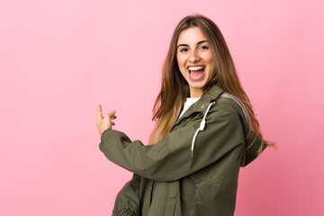 Young woman over isolated pink background pointing back