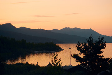 lake shore covered with trees in the mountains at sunset
