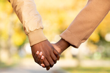 Romantic african american couple holding hands outdoors, closeup