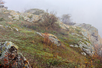 Pile of huge stones of rocks in the autumn fog at sunrise