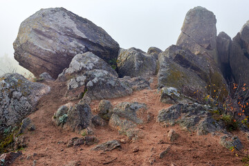 Pile of huge stones of rocks in the autumn fog at sunrise