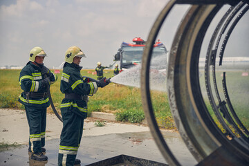 Fire brigade wearing protective uniform learning fight fire on the engine of plane