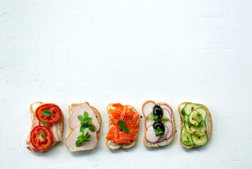 Fresh multicolored sandwiches with vegetables, fish and meat on a white plateImage Сopy space ....