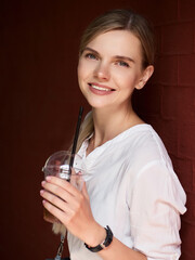 Outdoor summer city lifestyle portrait of young trendy dressed blonde happy woman with lemonade drink having fun outdoor in the city ready for travel