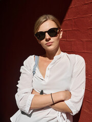 Outdoor summer city lifestyle portrait of young trendy dressed blonde happy woman in sunglasses having fun outdoor in the city ready for travel