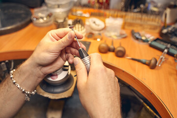 Professional jeweler holding a polishing instrument in his hand