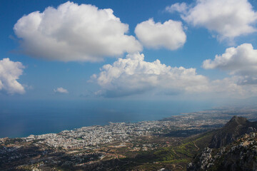 Fototapeta na wymiar View from the castle of Saint Hilarion on the city of Kyrenia, mountains, fluffy clouds and the Mediterranean sea. Cyprus.