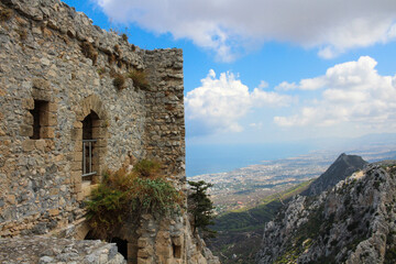 Fototapeta na wymiar Stone walls with arches of the castle of Saint Hilarion against a blue sky with clouds. The mountains of Cyprus and the view down to Kyrenia and the Mediterranean sea. Cyprus.
