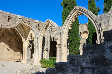 Fototapeta premium Arches of Bellapais Abbey, White Abbey, Abbey of the Beautiful world. Cypress trees against a blue sky.