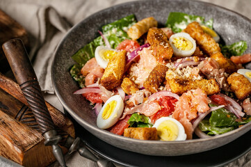 Close-up of Caesar salad with red fish, romaine lettuce, quail eggs and garlic croutons.