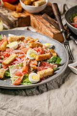 Close-up Caesar salad with salted salmon, romaine lettuce, quail eggs, garlic croutons. Vertical shot