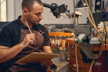 Thoughtful jewelry designer sitting at the workbench