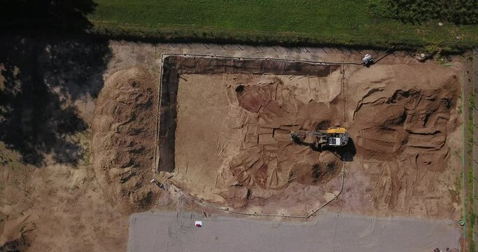 Bagger auf einer Baustelle hebt einen Keller aus. Tiefbau, Erdbau, Auskoffern aus der Vogelperspektive