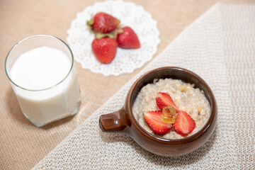 porridge oatmeal with strawberries, strawberries and a glass of milk